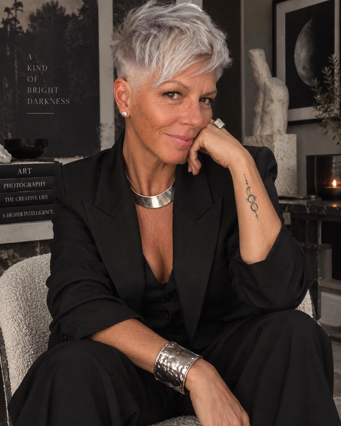 PHLUX, seated in a black suit and silver jewelry